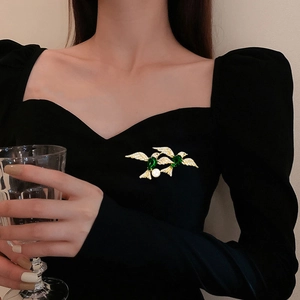 Elegant emerald bird brooch with pearls and zircons on black velvet dress