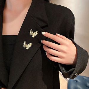 Elegante gouden vlinderbrocheset met emaille op de revers van een zwart pak