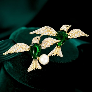 Luxurious green bird brooch in gold with sparkling crystals and a white pearl drop