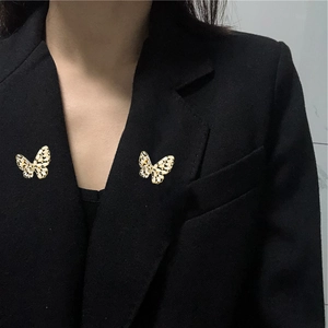Elegante goudkleurige vlinderbroches met zwart-wit emaille op de revers van een blazer