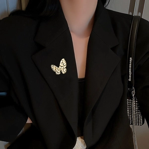 Elegante gouden vlinderbroche met zirkonia-details op zwarte blazerrevers voor dames