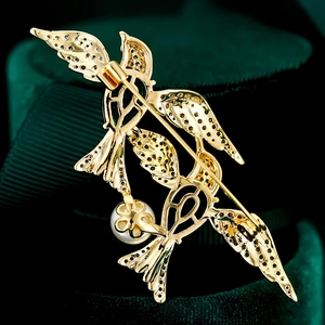 Macro view of golden bird brooch showing the secure rotating safety clasp and craft details