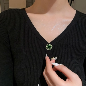 Elegant green flower zircon brooch pinned on a black V-neck knit shirt for styling