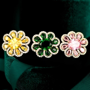 Detailed macro view of crystal flower brooches in yellow, green, and pink finishes
