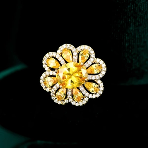 Exquisite flower brooch with yellow oval center stone and pear-shaped petals on green velvet
