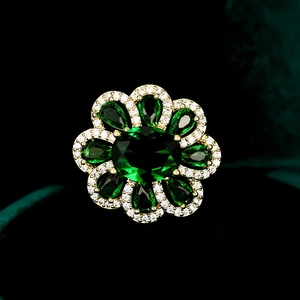 Macro shot of luxury gold floral brooch with emerald green gemstones and zircon detailing