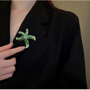 Exquisite starfish brooch with green and white zircons pinned on a black suit lapel