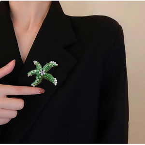Macro detail of a starfish brooch with green zircons pinned on a black suit lapel