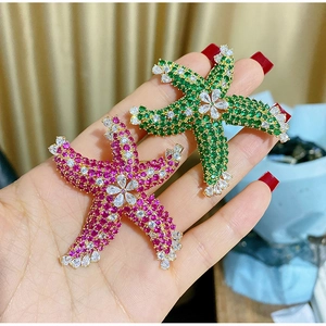 Macro shot of colorful starfish brooches with emerald and rose zircon crystal inlay
