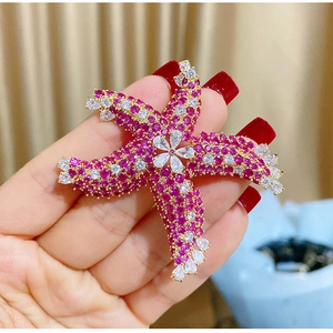 Detailed view of starfish brooch with pink cubic zirconia and gold plating finish