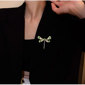 Eleganter Libellen-Anstecknadel mit grünen Zirkonias und Strasssteinen auf einem Blazer
