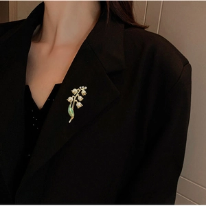 Broche muguet élégante avec feuilles vertes épinglée sur le revers d'un blazer noir