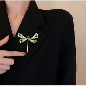 Eleganter Libellen-Anstecker mit grünen Edelsteinen und Zirkonia am schwarzen Blazer