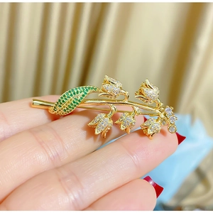 Détail de la broche muguet avec cristaux verts et finitions en métal doré