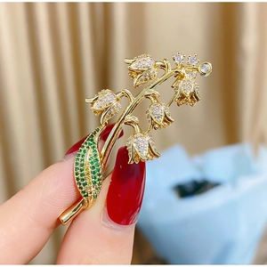 Détail macro de la broche muguet avec placage d'or et cristaux incrustés
