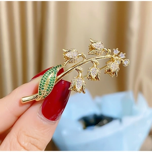 Broche muguet élégante avec feuilles vertes et fleurs en cristal sur métal doré