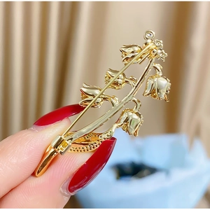 Détail de l'épingle au dos et texture dorée de la broche en forme de muguet