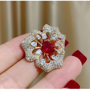 Nahaufnahme der eleganten Blumenbrosche mit rotem Edelstein und Kristallblüten