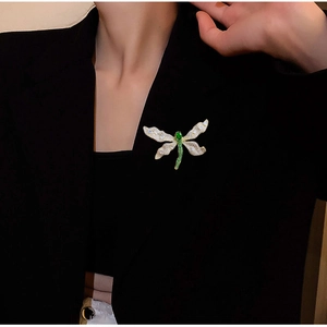 Elegante spilla a libellula verde con cristalli bianchi su blazer nero di lusso