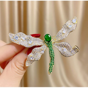 Dettaglio della spilla a libellula con gemme verdi e cristalli brillanti incastonati