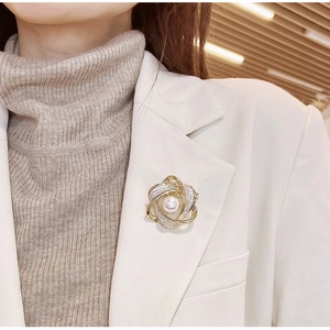 Broche fleur dorée élégante avec perle et cristaux sur un blazer de couleur crème