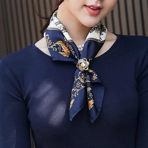 Attache-foulard dorée en spirale avec perle sur une écharpe en soie bleue élégante