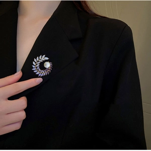 Elegant gold brooch with purple crystals and pearl pinned on a black suit jacket