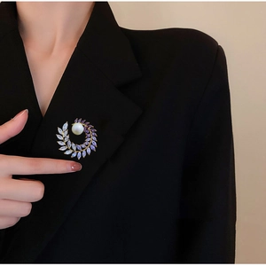 Luxurious leaf-shaped pearl brooch with purple zircon crystals on a black suit jacket