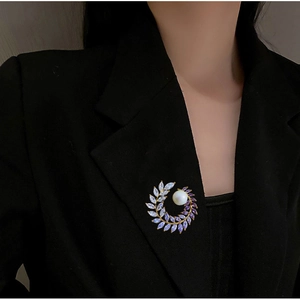 Detail of elegant pearl wheat wreath brooch with purple crystals on black blazer