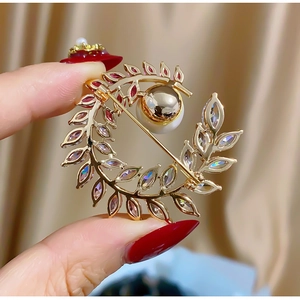 Detailed close-up of a golden moon brooch with pearl and sparkling leaf-shaped crystals