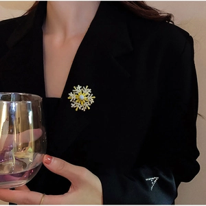 Detailed close-up of a rotating snowflake brooch with zircon on a black blazer lapel
