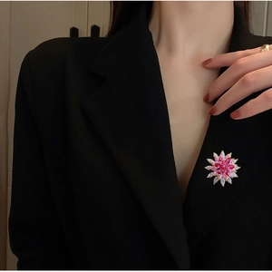 Elegant rotating snowflake brooch with pink and white crystals on a black suit jacket