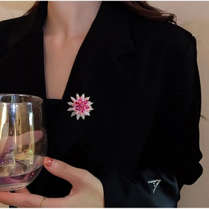 Close-up of a pink floral rotating snowflake brooch on a black suit lapel
