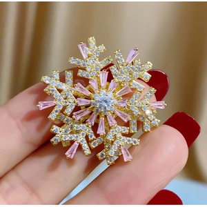 Detailed shot of snowflake brooch with pink cubic zirconia and gold plating