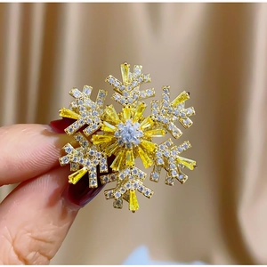 Elegant rotating snowflake brooch with gold metal and yellow zircon crystals in hand