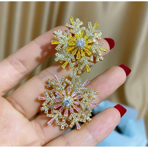 Macro shot of 3D snowflake brooches with yellow and pink cubic zirconia on a warm fabric