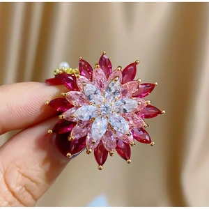 Macro shot of tiered rotating flower brooch with red and pink marquise gems in gold