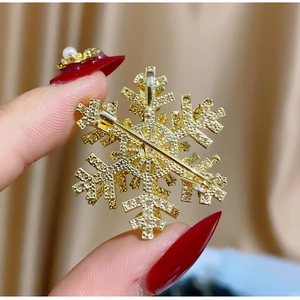 Detailed back view of gold snowflake brooch showing secure pin fastener mechanism