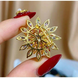 Macro detail of the rotating snowflake brooch showing the gold-plated clasp and frame