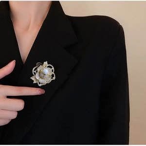 Détail d'une élégante broche rose dorée avec zircons AAA scintillants et une perle blanche