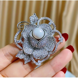 Gros plan sur la broche rose en zircon AAA étincelant avec un centre en perle