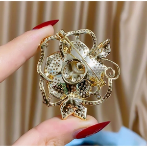 Détail du dos d'une broche fleur évidée dorée montrant le fermoir à épingle sûr