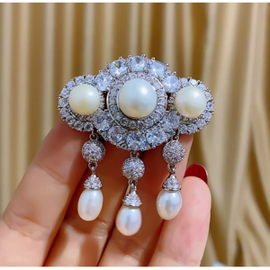 Elegant silver brooch with three round white pearls and dangling teardrop tassels