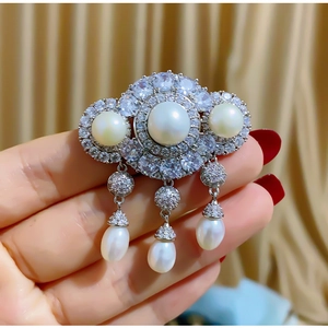Macro detail of luxury pearl brooch with sparkling zircons and elegant tassel pendants