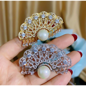 Elegant fan-shaped brooch set with rhinestones and white pearls in gold and silver finish