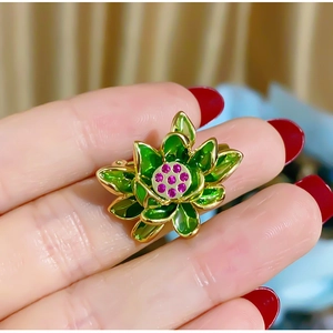 Detailed macro of vintage lotus brooch with green enamel petals and pink zircon stones