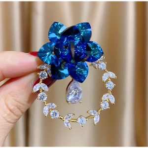 Elegante spilla a ghirlanda floreale dorata con cristalli blu scuro e zirconi chiari