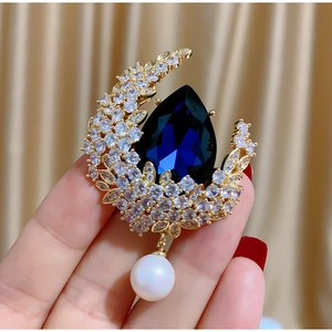 Elegante spilla a luna dorata con gemma blu a goccia e perla bianca pendente