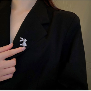 Detailed close-up of a silver bunny brooch with white zircons on a black suit lapel