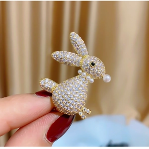 Golden bunny brooch with micro-pave crystals and pearl details held in hand